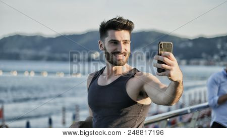 Young Man At Beach Taking Selfie Photo With His Cell Phone