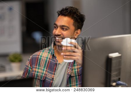 deadline and people concept - smiling creative man working and drinking coffee at night office