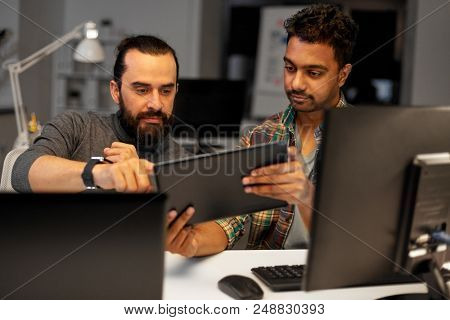 deadline, technology and people concept - creative team with tablet pc computer working together late at night office