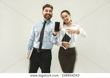 Happy Boss. Man And His Secretary Standing At Office Or Studio. Business Man Showing The Phone To Ca