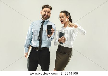 Happy Boss. Man And His Secretary Standing At Office Or Studio. Business Man Showing The Phone To Ca