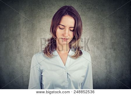 Young Pretty Woman In Shirt Looking Down In Gloomy And Depressed Emotions Looking Upset On Gray Back