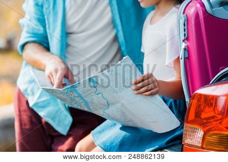 Cropped Image Of Father And Daughter Looking At Map At Car Trunk