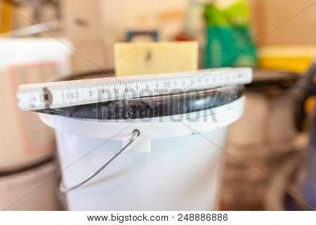 Double Meter Stick Lies On A White Bucket