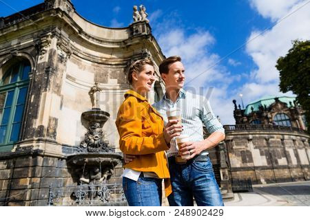 Tourist couple in Dresden at Zwinger with coffee taking walk
