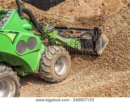 Green skid loader loading gravel
