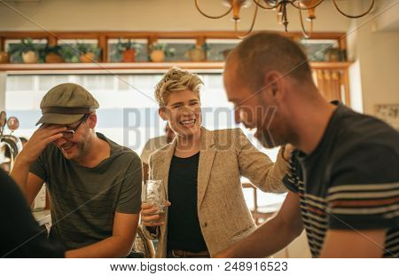 Group Of Young Friends Laughing And Talking Over Drinks While Hanging Out Together In A Trendy Bar
