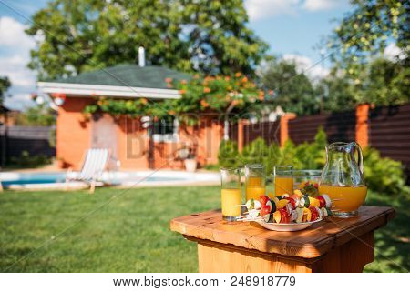 Selective Focus Of Fresh Vegetables For Barbecue And Glasses Of Juice On Backyard