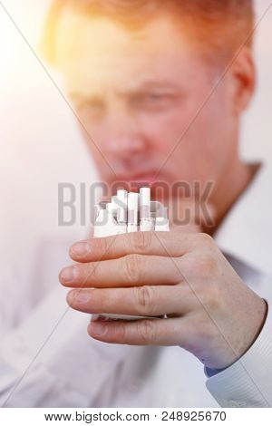 background image of serious businessman holding an open pack of cigarettes