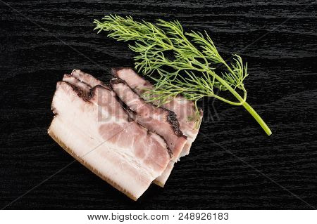 Group Of Three Slices Of English Bacon With A Spring Of Dill Flatlay On Black Wood