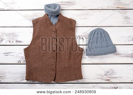 Woolen Sweater In Brown Jacket And Hat. Grey And Brown Winter Clothing. White Wooden Background, Fla