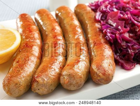 A Platter With German Thuringer Sausage Or Bratwurst, With Spiced Red Cabbage And Lemon.
