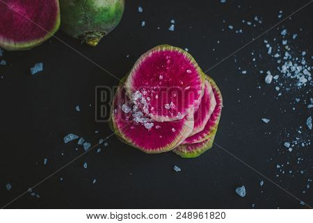 Watermelon Radishes Sliced, Sprinkled With Sea Salt On A Black Background