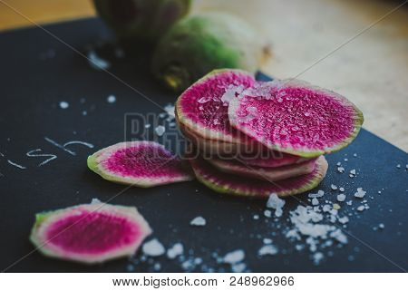 Watermelon Radishes Sliced, Sprinkled With Sea Salt On A Black Background