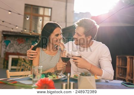 Glasses Of Wine. Happy Young Couple Feeling Loved And Excited While Clanging Their Glasses Of Red Wi