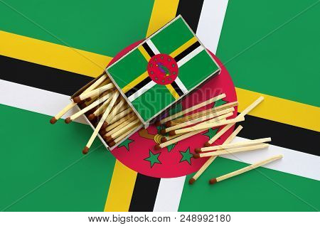 Dominica Flag  Is Shown On An Open Matchbox, From Which Several Matches Fall And Lies On A Large Fla