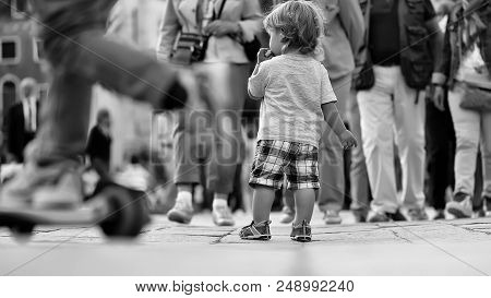 Lost Child. Photo Back View Of Cute Fair-haired Blond Kid Tiny Little Child Baby Boy Eating Bun Stan