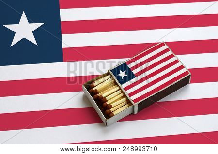 Liberia Flag  Is Shown In An Open Matchbox, Which Is Filled With Matches And Lies On A Large Flag.