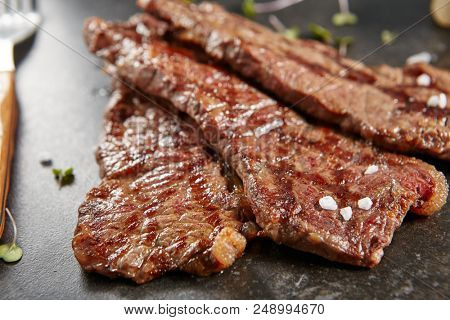 Hot Grilled Whole Gaucho Steak on Black Stone Background. Fresh Juicy Medium Rare Beef Grillsteak. Barbecue Meat Top View Close Up