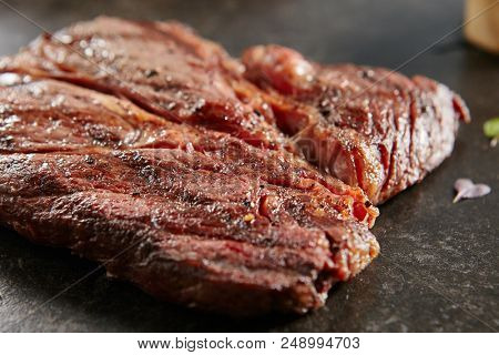 Hot Grilled Whole Alternative Steak or on Black Stone Background. Fresh Juicy Medium Rare Beef Grillsteak. Barbecue Meat Close Up