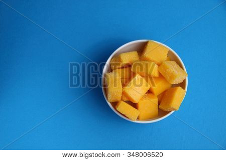 White Bowl Of Mango Succades Isolated On Blue Background Flat Lay. Image Contains Copy Space