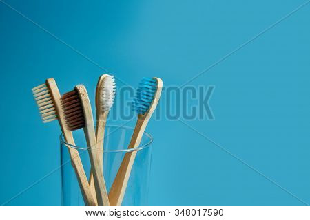 Wooden Toothbrushes With A Glass Cup On A Blue Background With Copy Space.