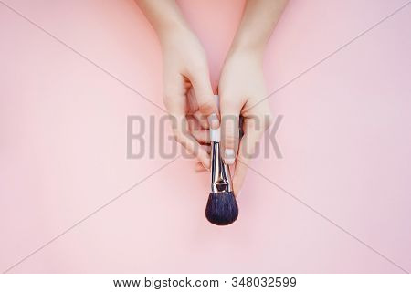Female Hand With Makeup Brushes On Pink Color Background. Top View Point, Flat Lay
