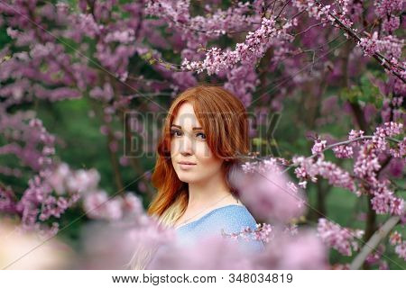 Beautiful Smilling Redhead Woman In Spring Time Blossom Cherrytrees Garden.