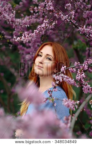 Beautiful Smilling Redhead Woman In Spring Time Blossom Cherrytrees Garden.