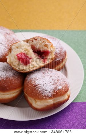 Sweet fat donuts on Mardi Gras purple, green, and yellow background. Traditional Mardi Gras food in America and Europe
