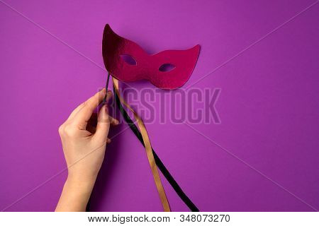 Woman Hand Holding  Festive, Colorful Mardi Gras Or Carnivale Mask Over Purple Background. Party Inv