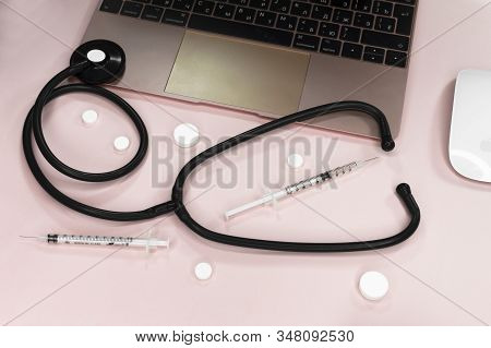 Doctors Desk With Stethoscope Keyboard Notepad And Pen, Prescription And Pills Top View On Pinck Bac