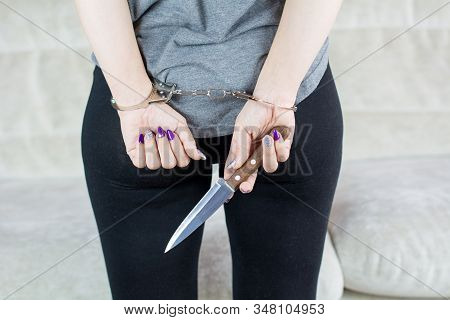 Arrested Woman Holding A Knife. Handcuffed Hands At The Back.