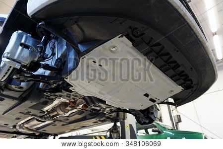 White Luxury Car Raised On A Lift In Service. An Additional Crankcase Protection Is Installed On The