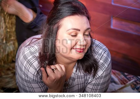 Portrait Of Fat Plump Fun Charming Cute Woman With Black Hair In The Room With Hay And Straw