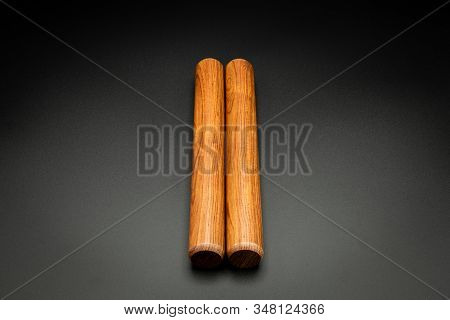 Closeup Of A Pair Of Wooden Claves Lying On A Black Underground