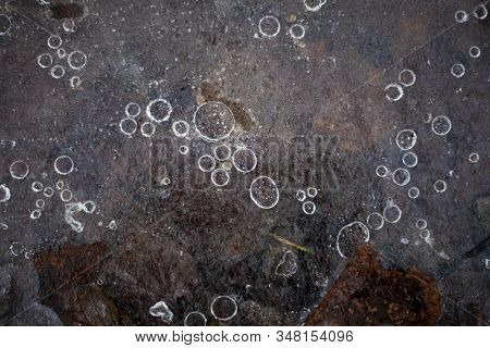Bubbles of air in frozen water. The texture of the ice in nature. Beautiful natural background of fr