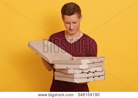 Image Of Disappointed Upset Handsome Young Boy Holding Cardboxes, Opening Box With Pizza, Looking At