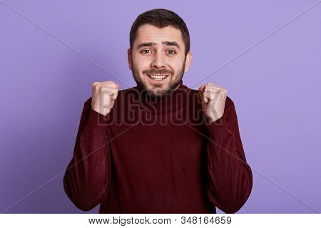 Indoor Portrait Of Emotional Charismatic Good Looking Man With Beard Clenching Fists, Making Gesture