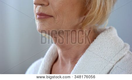 Elderly Woman Standing In Bath Robe And Looking In Mirror, Body Care, Close Up