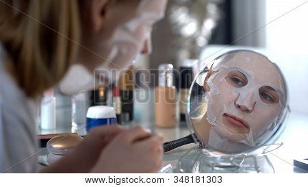 Girl Sitting With Face Mask, Smoothing Wrinkles And Making Skin Supple And Taut