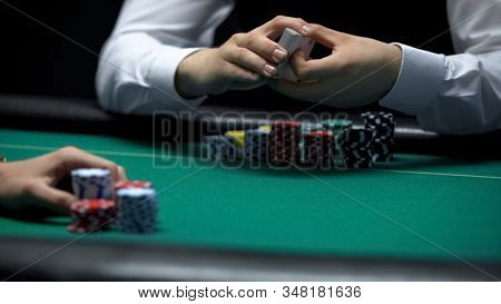 Professional Croupier Holding Deck Of Cards With Casino Client Ready To Make Bet