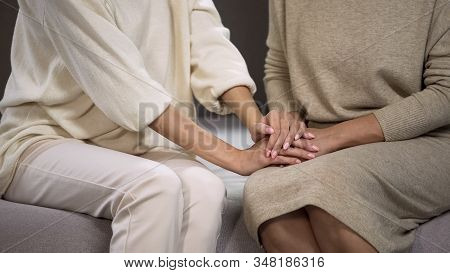 Young Lady Holding And Stroking Hand Of Senior Woman, Calming And Supporting