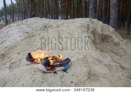 Burning Sports Sneakers Or Gym Shoes On Fire Stand On Sandy Beach Coast. Athlete Burned Out. Physica