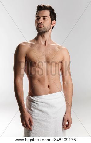 Photo of athletic half-naked man in bath towel posing and looking aside isolated over white background