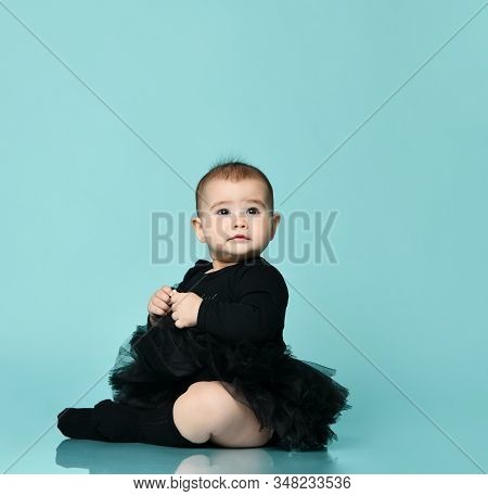 Little Child In Black Bodysuit With Pink Bow, Poofy Skirt And Socks. She Is Sitting On The Floor Aga
