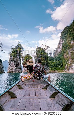 Couple Traveling By Boat Exploring Epic Limestone Cliffs In Huge Lake In Khao Sok National Park, Chi