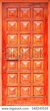 Old Wooden Entrance Doors With A Metal Bronze Handle, Framed On The Facade With Square Panels From T