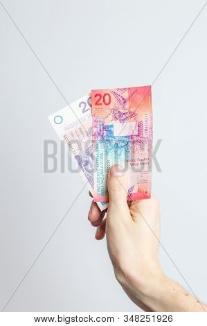 20 Pln And 20 Chf Banknotes Held In Hand.