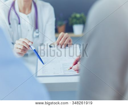 Doctor And Patient Examining A File With Medical Records, She Is Sitting On A Wheelchair